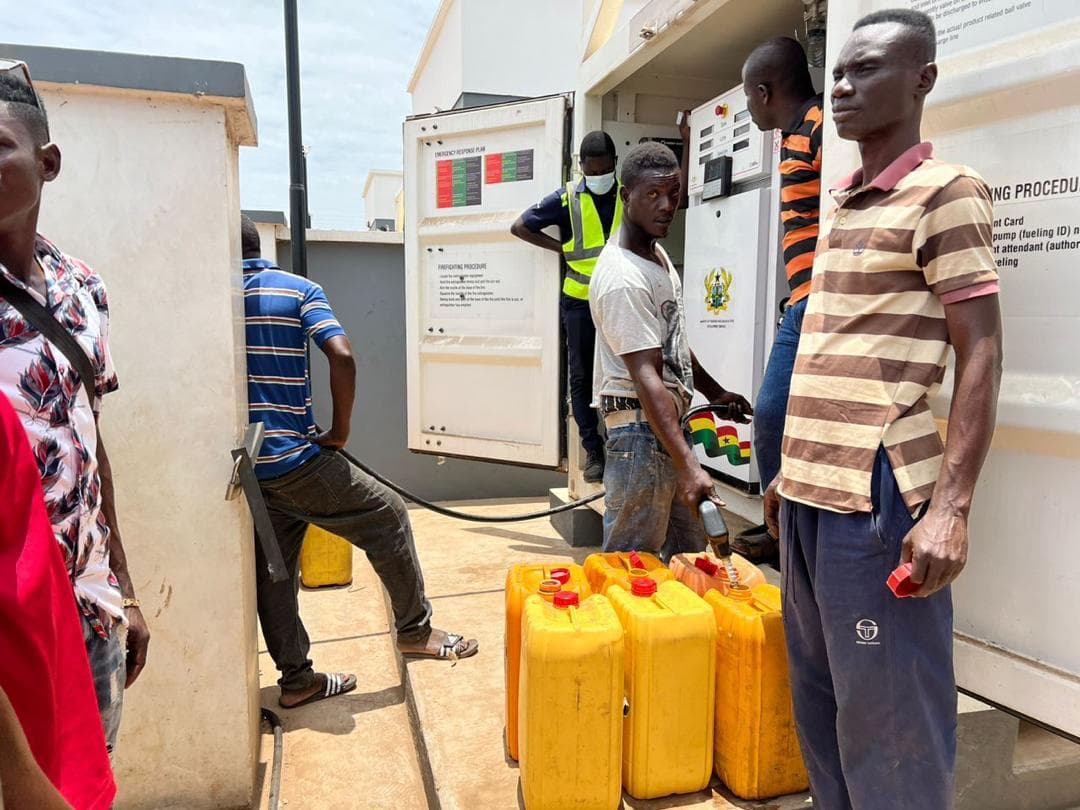 Man standing beside yellow fuel containers at an automated dispenser